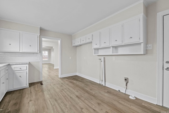 kitchen with light wood-type flooring, white cabinetry, and backsplash