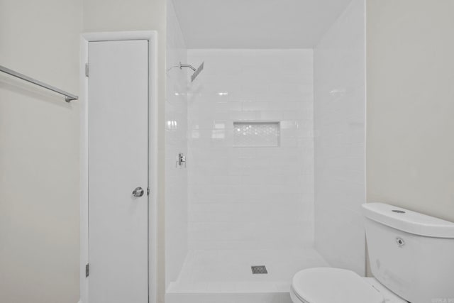 bathroom featuring a tile shower and toilet