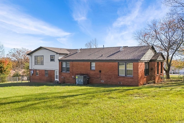 rear view of house featuring central air condition unit and a yard