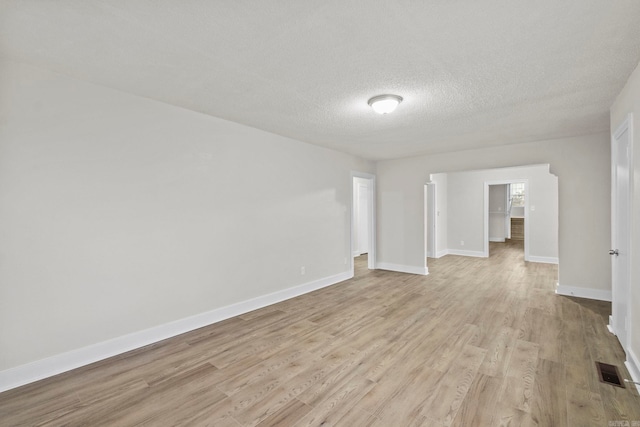 empty room with light hardwood / wood-style floors and a textured ceiling