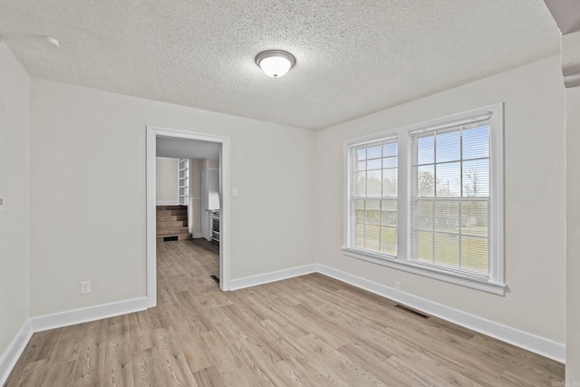 spare room featuring a textured ceiling and light hardwood / wood-style flooring