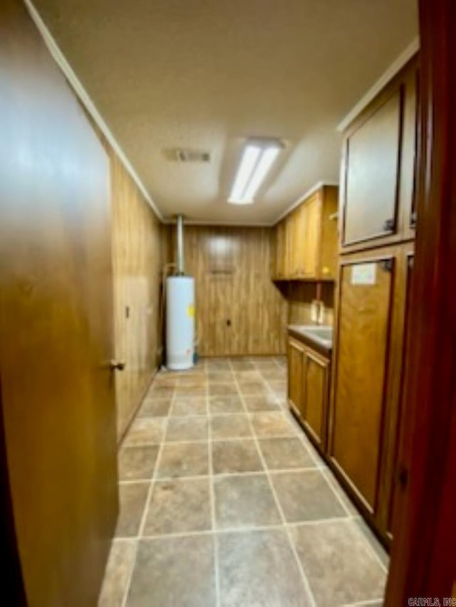 laundry room with gas water heater, crown molding, and wooden walls