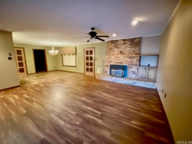 unfurnished living room featuring a fireplace, hardwood / wood-style floors, and ceiling fan with notable chandelier