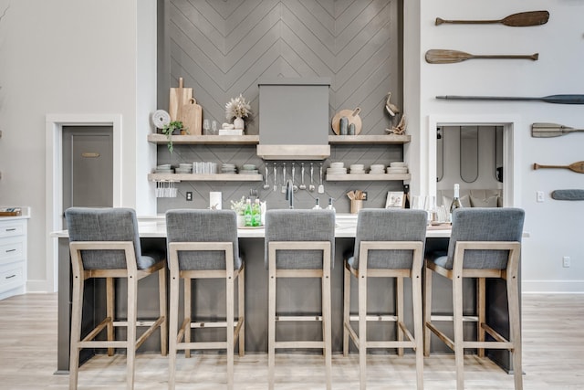 kitchen featuring a kitchen breakfast bar, backsplash, and light hardwood / wood-style flooring