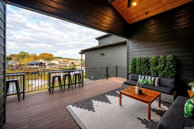 wooden deck with an outdoor living space, a water view, and an outdoor bar