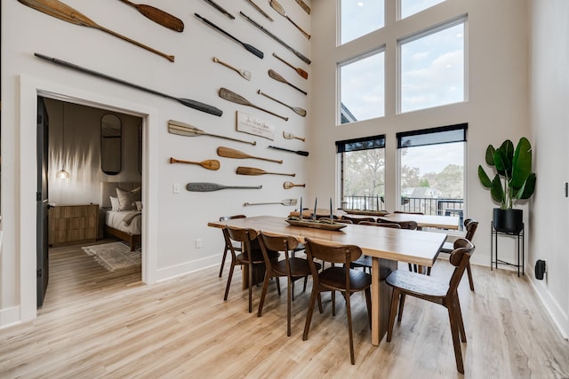 dining area featuring a towering ceiling and light hardwood / wood-style flooring