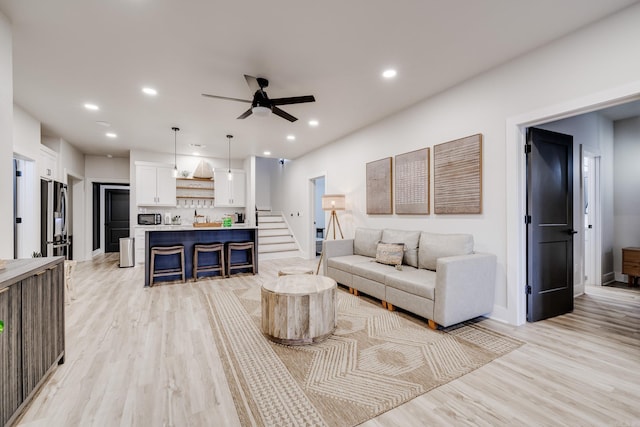 living room with light hardwood / wood-style flooring and ceiling fan