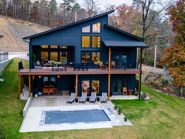 back of property featuring a lawn, a patio area, french doors, and a covered pool