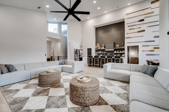 living room featuring a high ceiling, light hardwood / wood-style floors, and ceiling fan