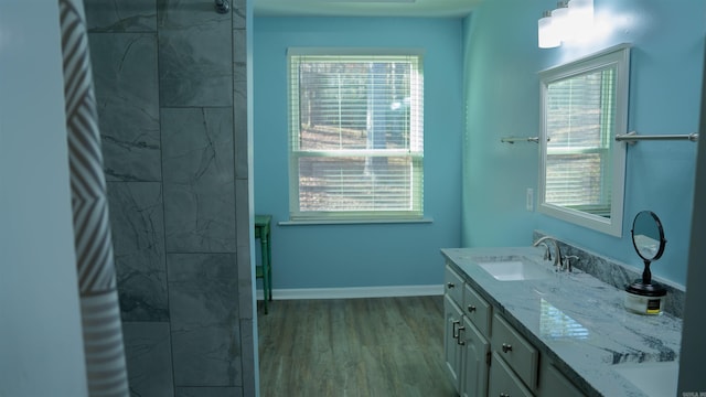 bathroom with hardwood / wood-style flooring, plenty of natural light, tiled shower, and vanity