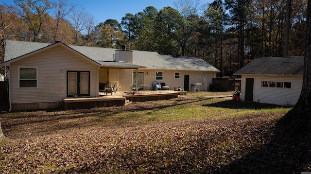 rear view of house with a lawn, a wooden deck, an outdoor structure, and a garage