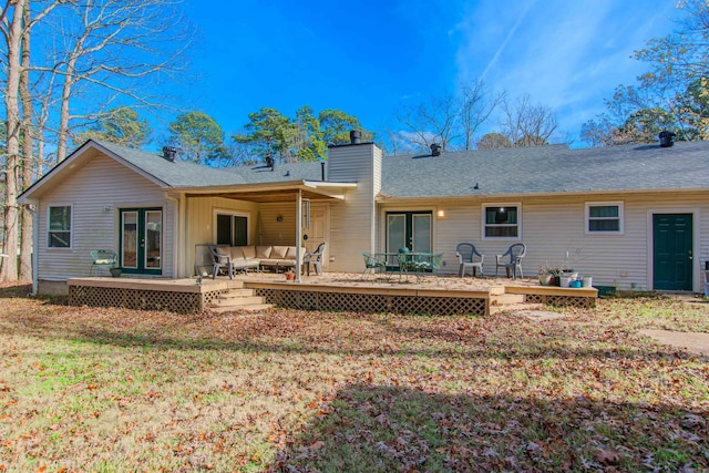 rear view of property featuring a lawn, an outdoor living space, a deck, and french doors