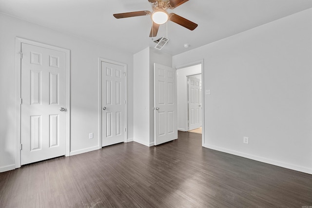 unfurnished bedroom with dark hardwood / wood-style floors, ceiling fan, and multiple closets