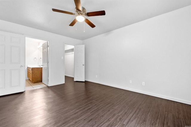 unfurnished bedroom featuring a walk in closet, ensuite bath, ceiling fan, dark hardwood / wood-style flooring, and a closet