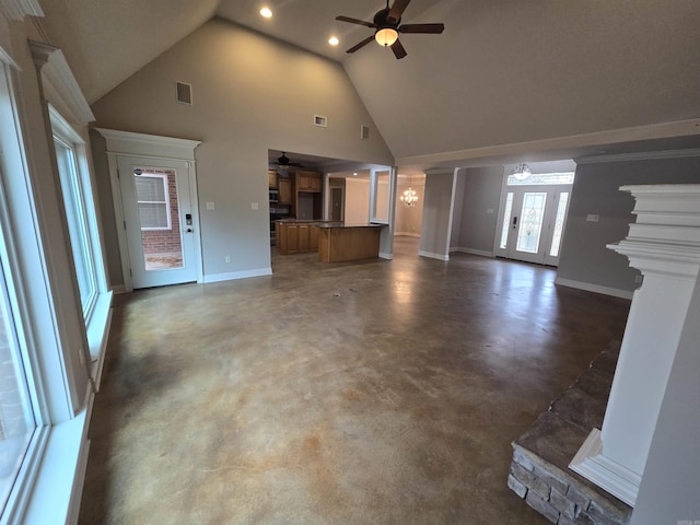 unfurnished living room with high vaulted ceiling and ceiling fan with notable chandelier