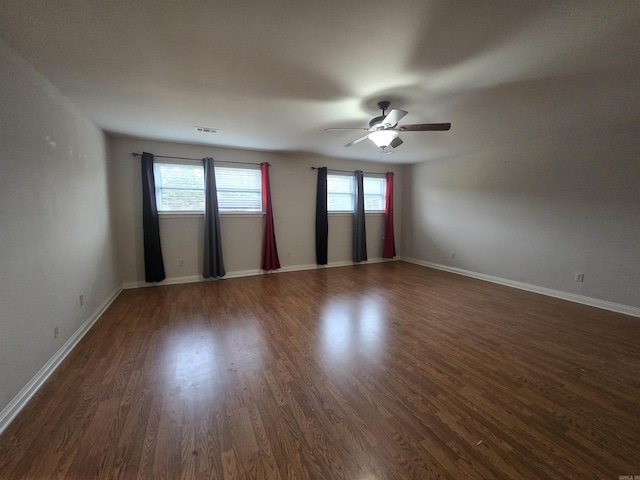 unfurnished room featuring ceiling fan, dark wood-type flooring, and a healthy amount of sunlight