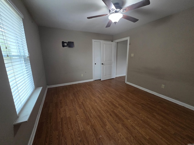 unfurnished bedroom featuring dark hardwood / wood-style floors, multiple windows, and ceiling fan