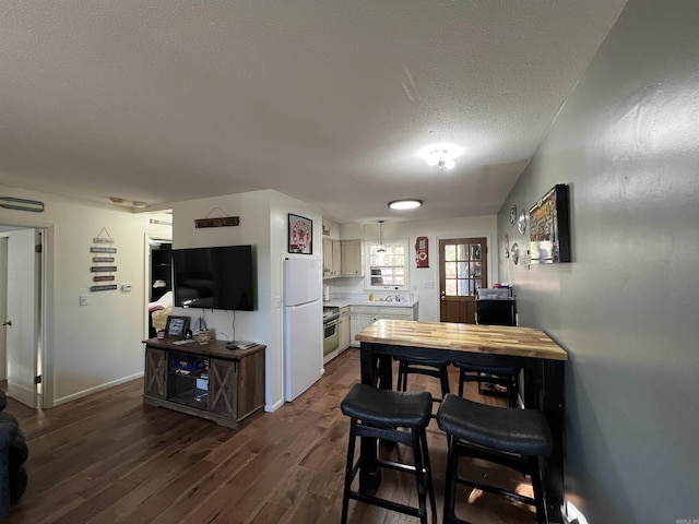 kitchen with a textured ceiling, dark wood-type flooring, white refrigerator, white cabinets, and stainless steel range with electric cooktop