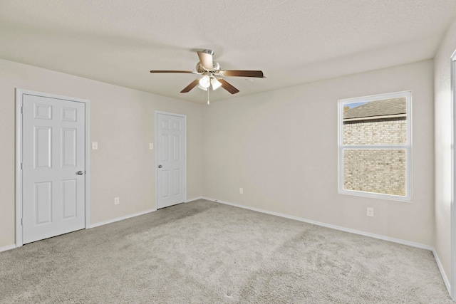 spare room featuring ceiling fan, light colored carpet, and a textured ceiling