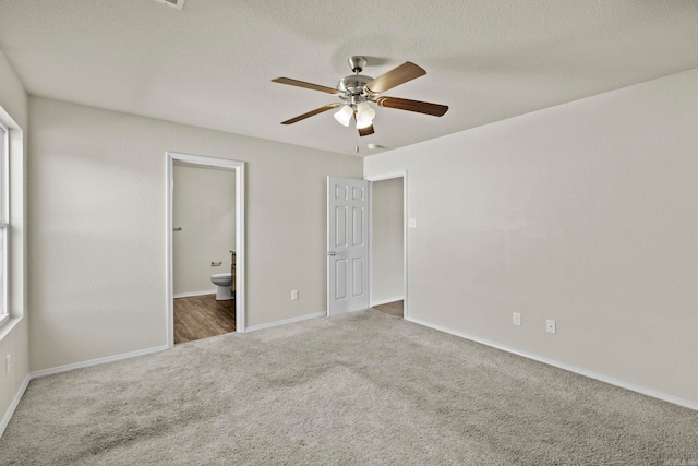 unfurnished bedroom featuring carpet, a textured ceiling, ensuite bathroom, and ceiling fan