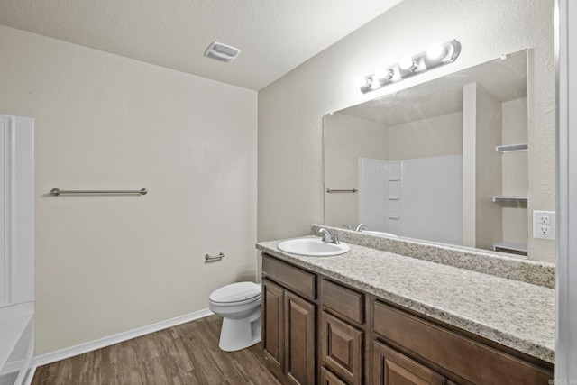 bathroom with hardwood / wood-style floors, vanity, a textured ceiling, and toilet