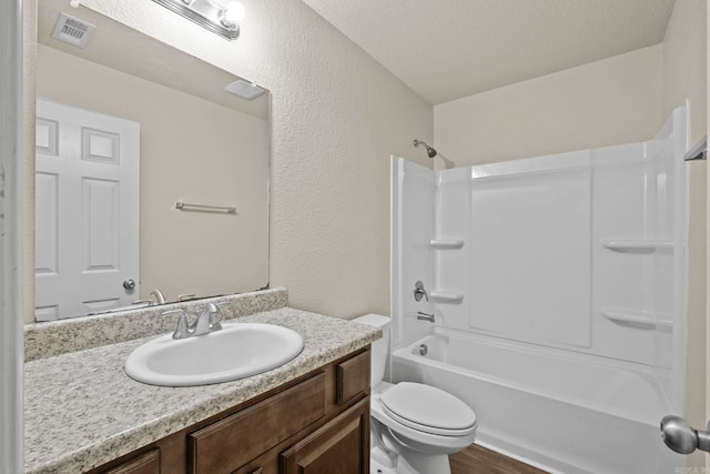 full bathroom with hardwood / wood-style floors, vanity, shower / washtub combination, toilet, and a textured ceiling