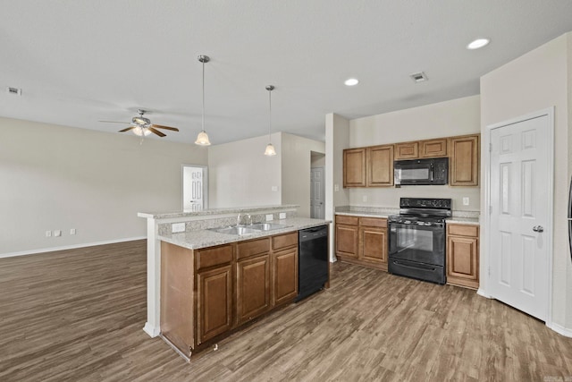 kitchen with black appliances, dark hardwood / wood-style floors, sink, and a kitchen island with sink