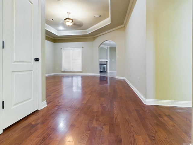 interior space with dark hardwood / wood-style flooring, a raised ceiling, crown molding, and a tiled fireplace