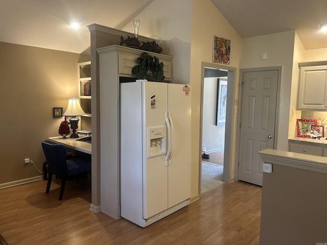 kitchen with white cabinets, light hardwood / wood-style flooring, white fridge with ice dispenser, and lofted ceiling