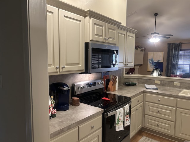 kitchen with ceiling fan, sink, stainless steel appliances, kitchen peninsula, and light wood-type flooring