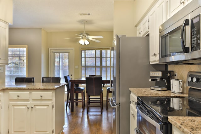 kitchen featuring light stone countertops, appliances with stainless steel finishes, dark hardwood / wood-style flooring, ceiling fan, and white cabinets