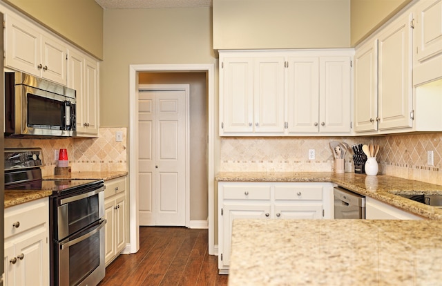 kitchen featuring white cabinets, backsplash, stainless steel appliances, and dark wood-type flooring