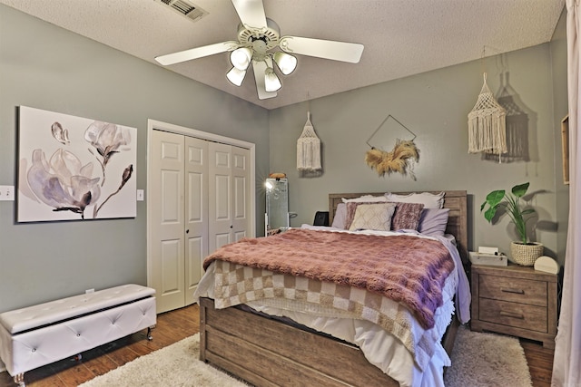 bedroom with a textured ceiling, a closet, ceiling fan, and dark hardwood / wood-style floors