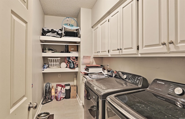 laundry area with cabinets, a textured ceiling, and separate washer and dryer