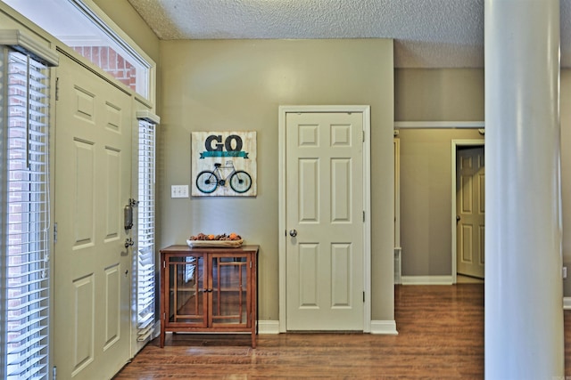 foyer entrance with dark hardwood / wood-style floors and a textured ceiling