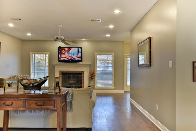 living room featuring dark hardwood / wood-style floors, ceiling fan, a wealth of natural light, and a brick fireplace