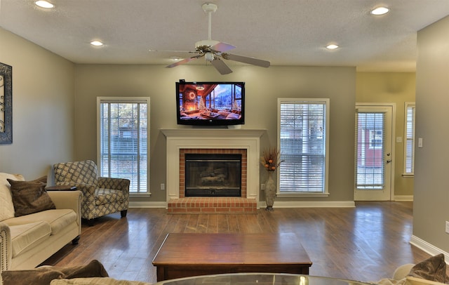 living room featuring dark hardwood / wood-style flooring, a brick fireplace, plenty of natural light, and ceiling fan