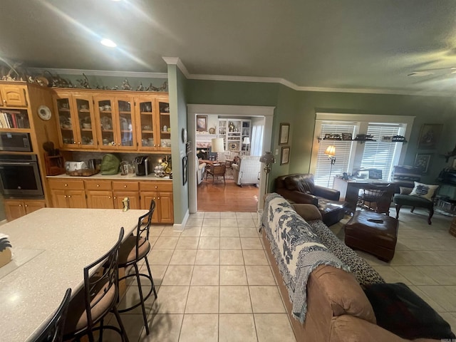 kitchen with oven, crown molding, light tile patterned floors, and built in microwave