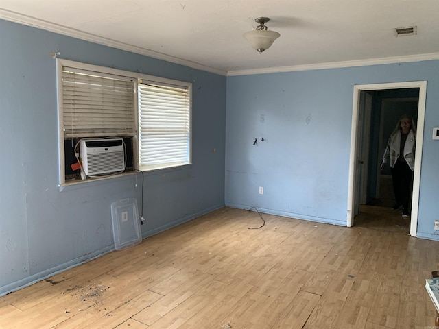 empty room featuring cooling unit, light hardwood / wood-style floors, and ornamental molding