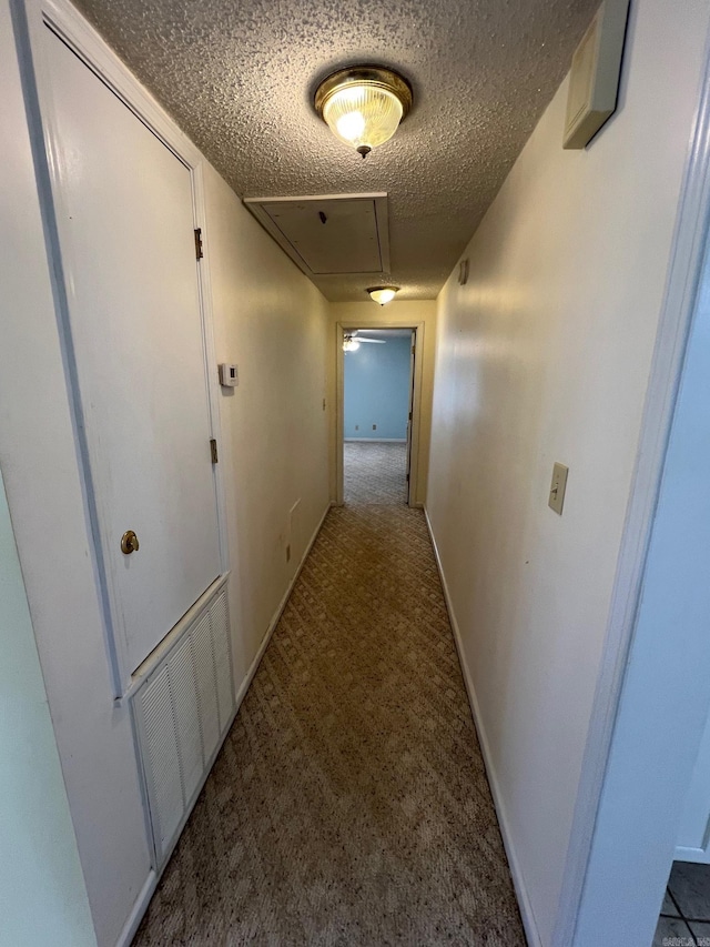 hallway with light carpet and a textured ceiling