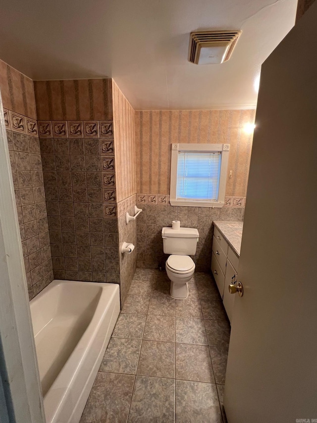 bathroom featuring a tub to relax in, vanity, tile walls, tile patterned flooring, and toilet