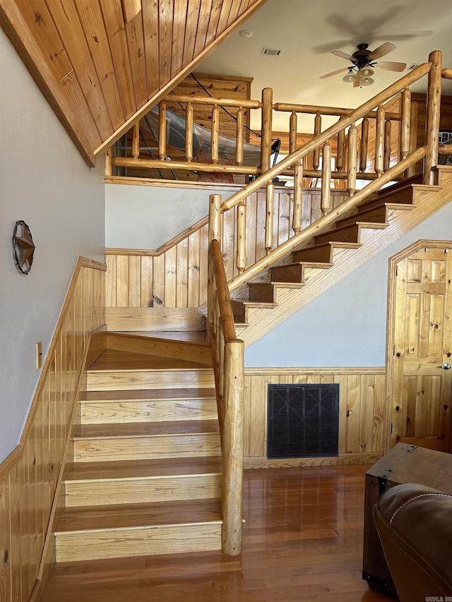 stairway with hardwood / wood-style floors, wooden ceiling, ceiling fan, wood walls, and lofted ceiling