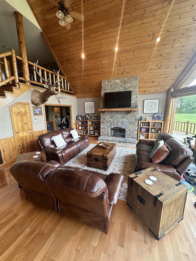 living room with a fireplace, wooden ceiling, light wood-type flooring, wood walls, and lofted ceiling