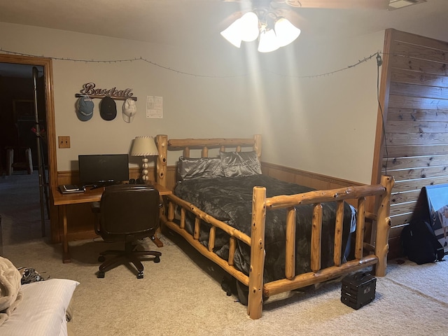 carpeted bedroom with wooden walls and ceiling fan