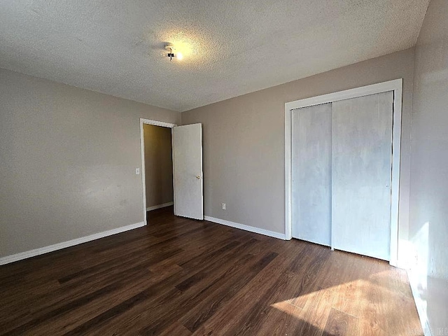 unfurnished bedroom with a textured ceiling, dark hardwood / wood-style floors, and a closet