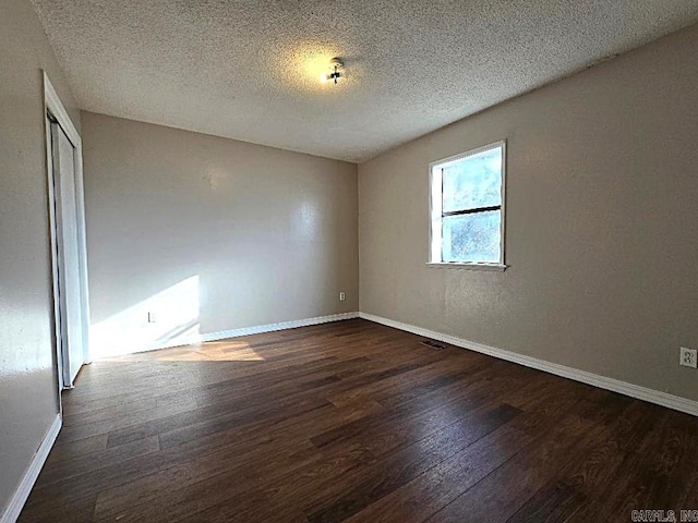 unfurnished room featuring a textured ceiling and dark wood-type flooring