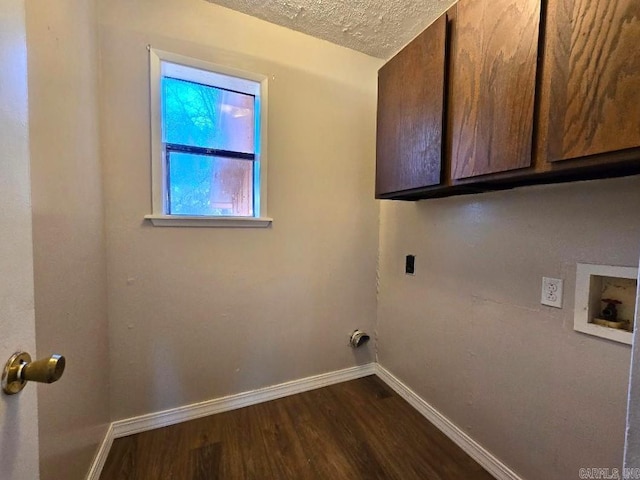 clothes washing area with a textured ceiling, cabinets, dark hardwood / wood-style floors, and washer hookup