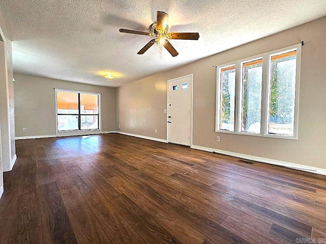 interior space with a textured ceiling, ceiling fan, plenty of natural light, and dark hardwood / wood-style floors