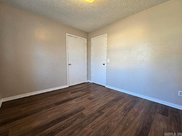 empty room with a textured ceiling and dark wood-type flooring