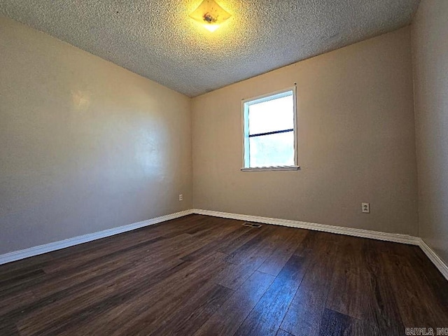 spare room featuring a textured ceiling and dark hardwood / wood-style flooring